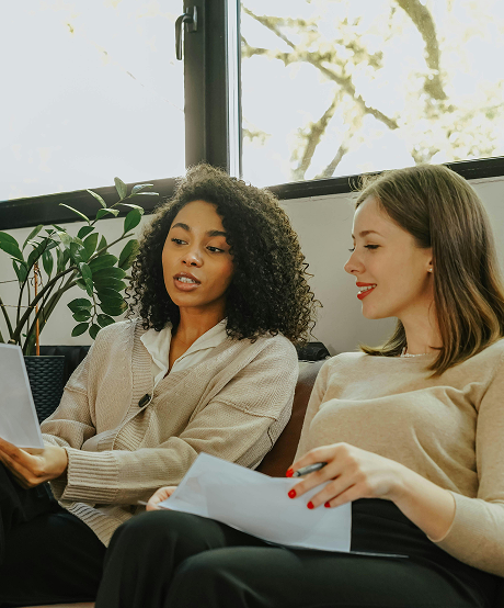 Two women on a couch discussing documents