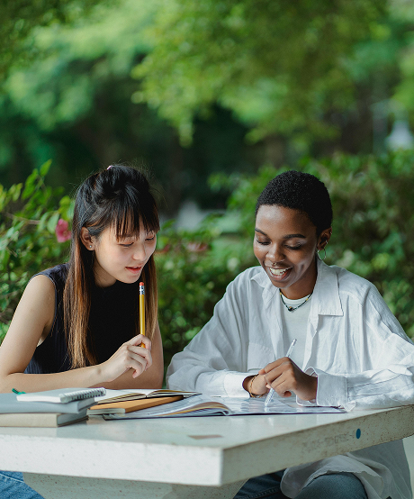 Two women sitting at a table outside studying
